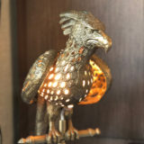 A golden lamp in the shape of the phoenix with holes in the feathers for light to shine through