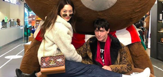 Claudia Kim and Ezra Miller pose on a cartoon bear.