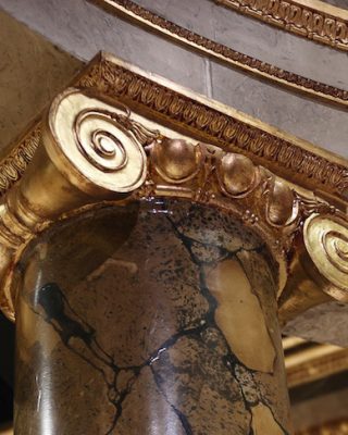 The incredible set design features a convincing marble effect and gold masonry.