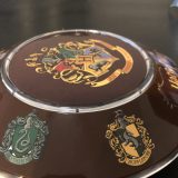 One side of the base has the Slytherin and Hufflepuff House crests.