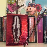 Harry Potter: Manage Your Mischief Marauder’s Map Sequin Notebook with alternate back cover partially revealed, displayed alongside “Harry Potter” books