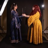 Rowena Ravenclaw and Helga Hufflepuff hold hands.