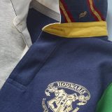 This close-up of the Mini Boden Hogwarts Rugby Shirt, multi-color, provides a better look at the collar design and Hogwarts crest in the front pocket area. It retails at £30.