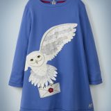 The Mini Boden Hedwig Post Dress in blue features a large, off-center image of Harry Potter’s beloved owl carrying a Hogwarts acceptance letter in her talons. It retails between £28 and £32.