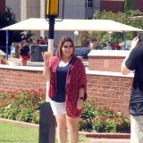 A University of Arizona student has her photo taken with the LEGO Golden Snitch she created in front of the signpost at the Back to Hogwarts event.