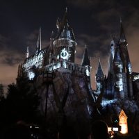 The Deathly Hallows symbol is projected onto the castle.