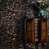 The Black family tapestry wallpaper shows flourishes of branches and leaves with small portraits of the Black family members.