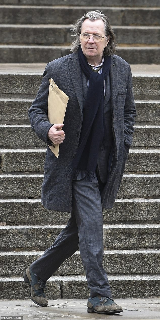 Gary Oldman carries a folder that possibly contains important spy stuff during filming for “Slow Horses.”