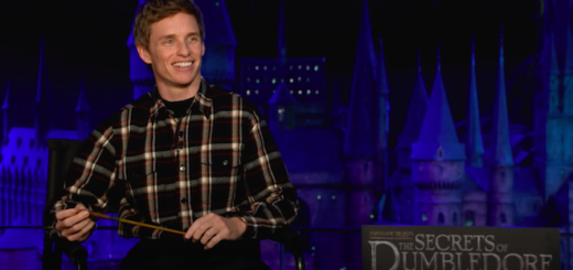 Eddie Redmayne sits in a chair in front of the model of Hogwarts at the Warner Bros. Studio Tour - The Making of Harry Potter.