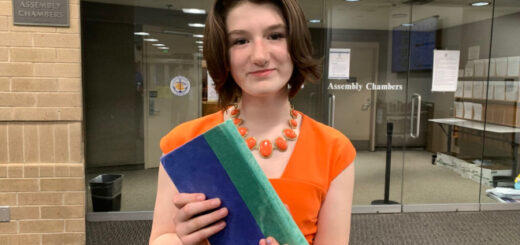 Janna Wilcox at the Anchorage Assembly chambers with a copy of “Harry Potter and the Chamber of Secrets” (Credit: Wesley Early and Alaska Public Media)
