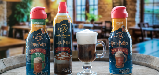 Coffee mate branded Butterbeer-flavor creamer bottles on a wooden table with a glass of foam-topped coffee between them