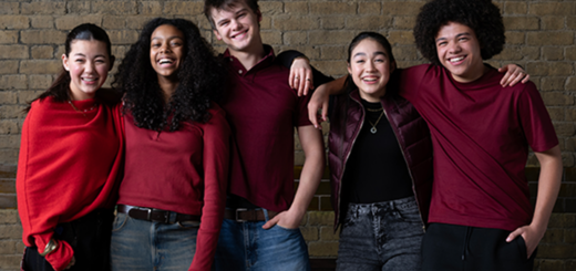 Five young actors in red clothing posing in front of a brick wall